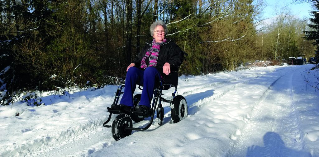 Frau in umgebauten Rollstuhl im Schnee