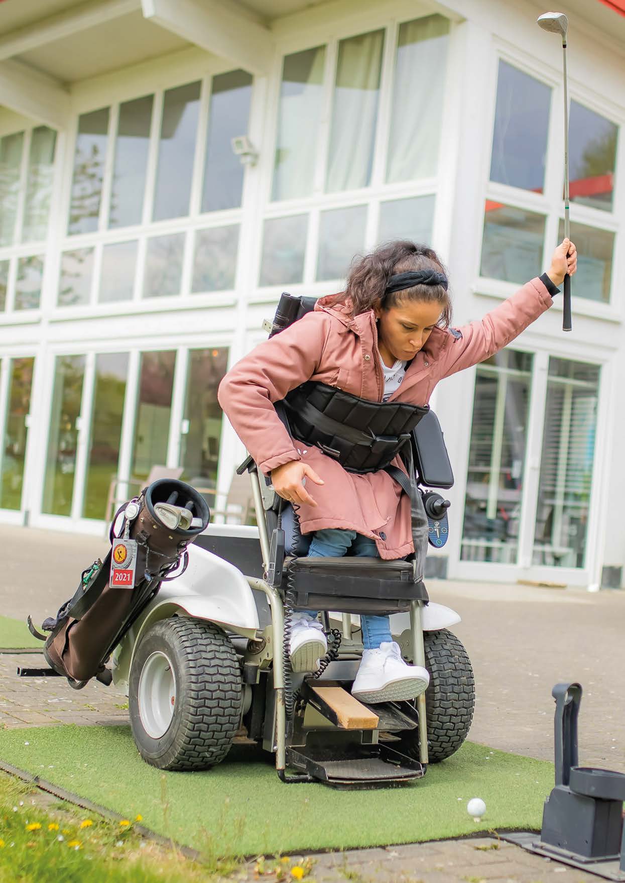 Rollstuhlfahrerin beim Para-Golfen, mit Golfschläger nach oben
