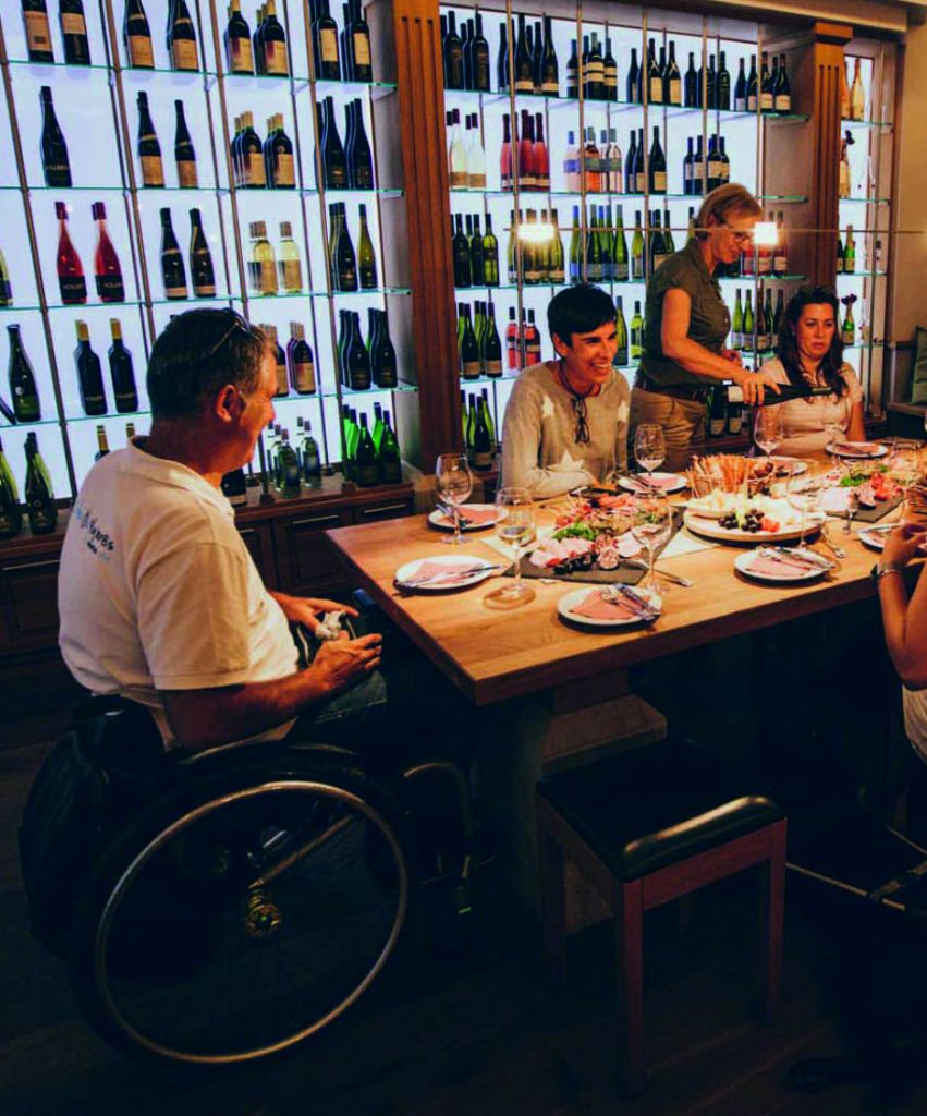 Mehrere Personen sitzen gemeinsam im Weinkeller an einem gedeckten Tisch